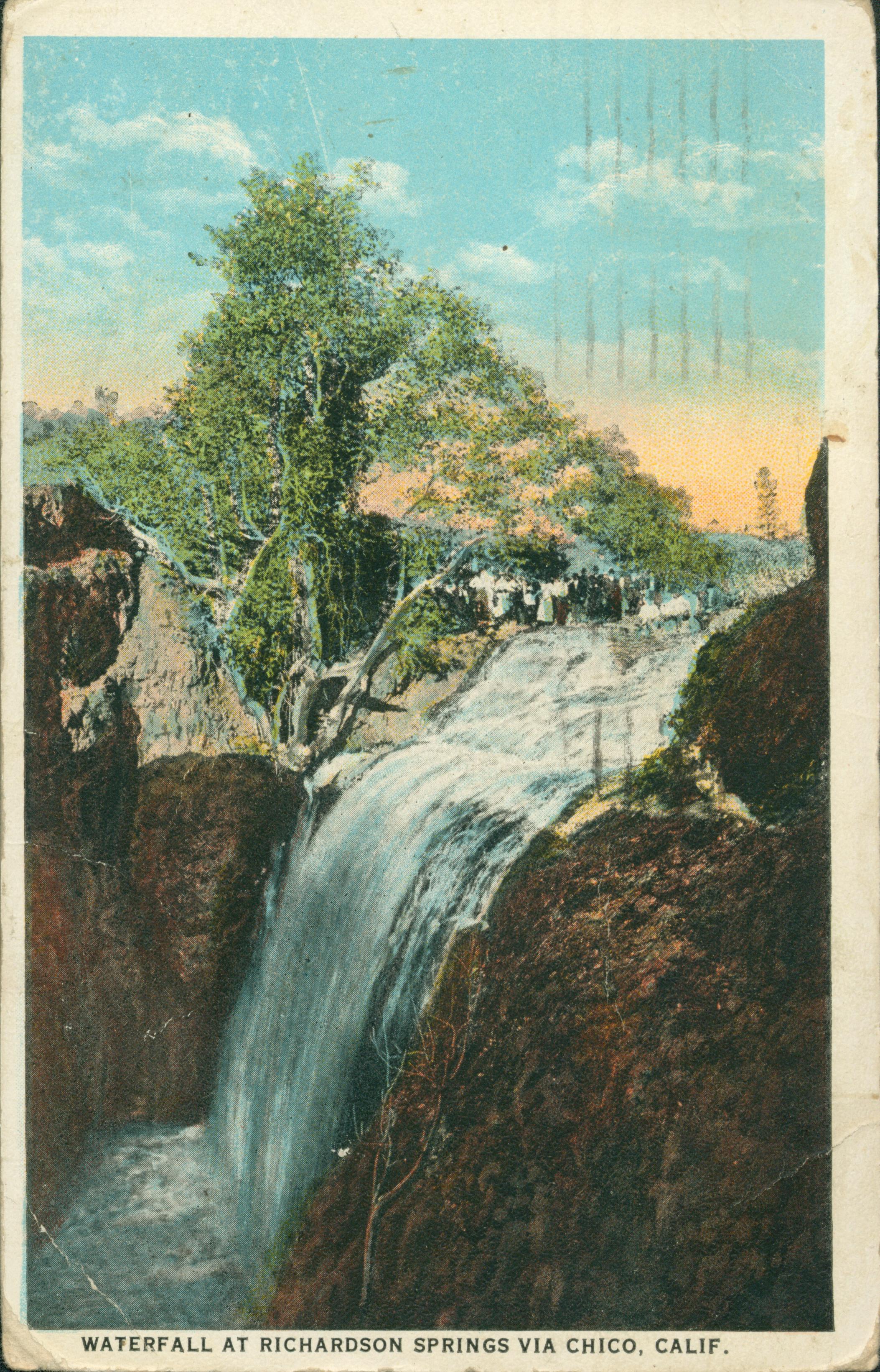Shows a waterfall with several onlookers standing under a tree