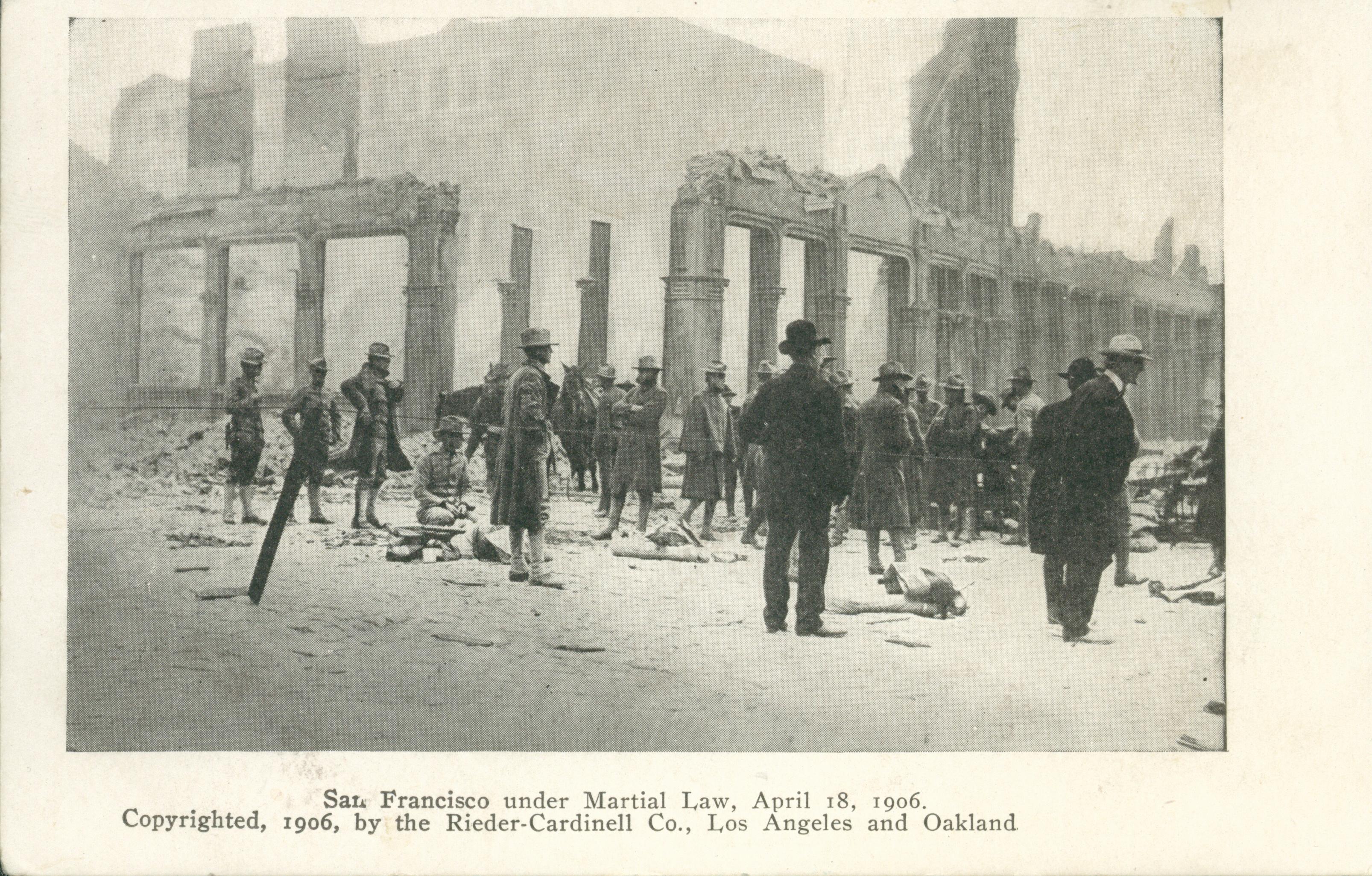 Shows a group in front of a collapsed building.