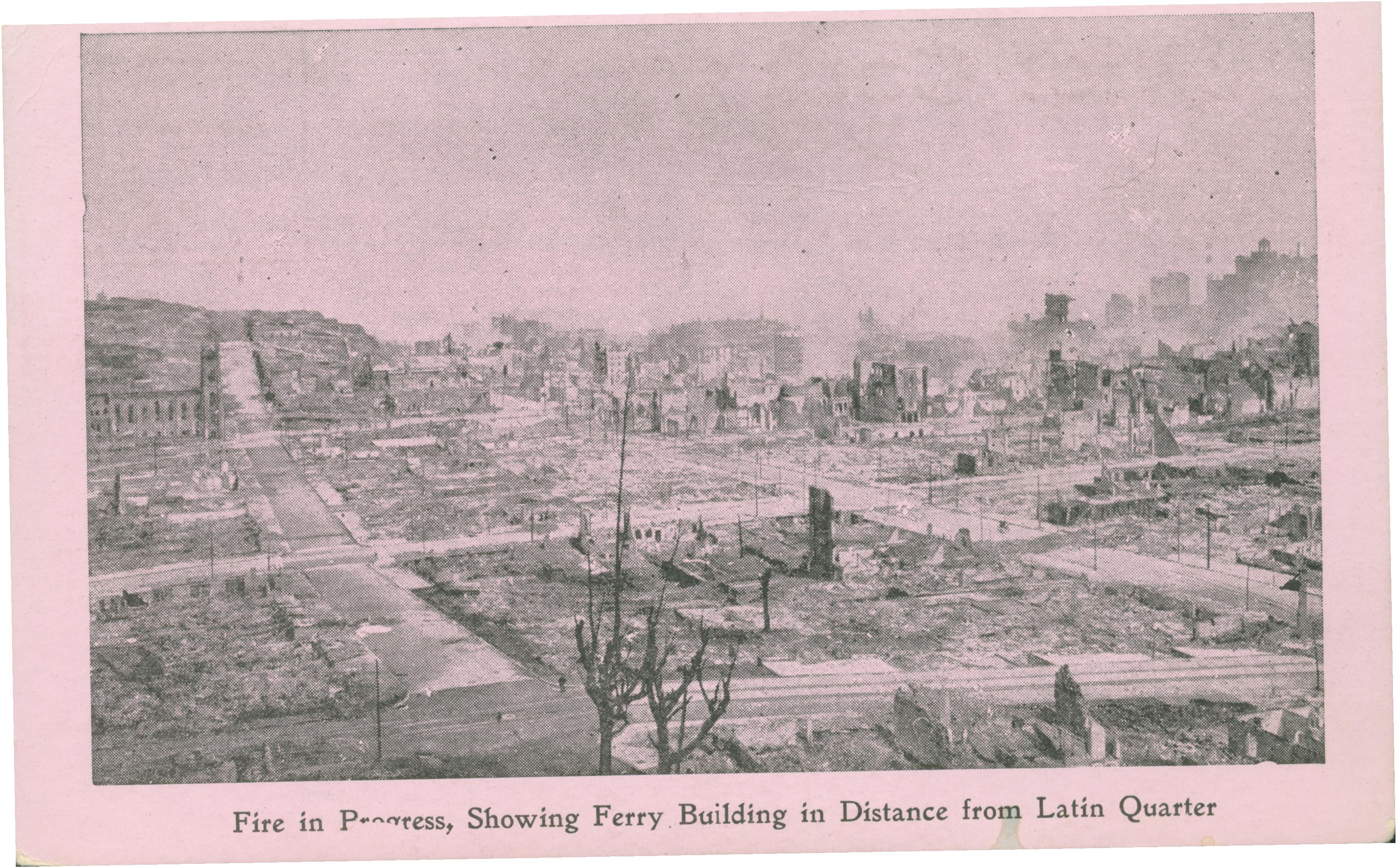 Shows a wide angle view of smoke rising above ruined buildings.