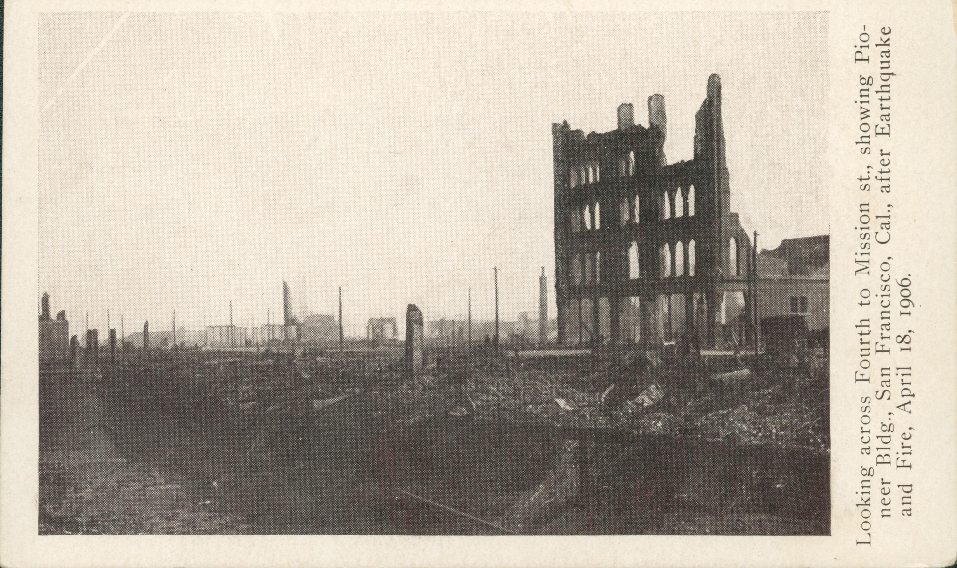 Shows a street lined by rubble with one building barely standing.