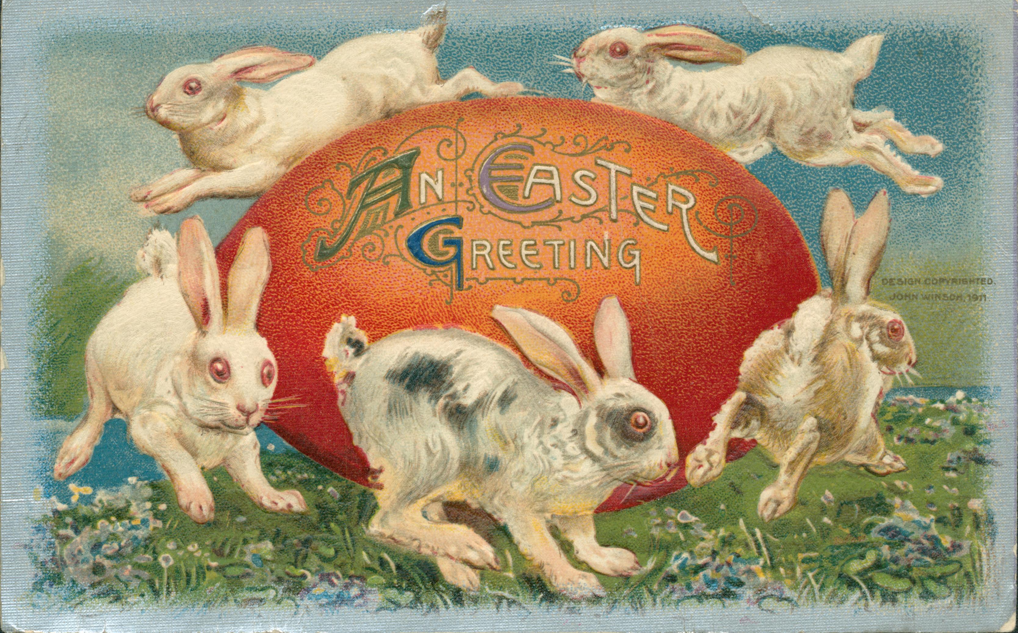 Five rabbits hopping around a large red egg.