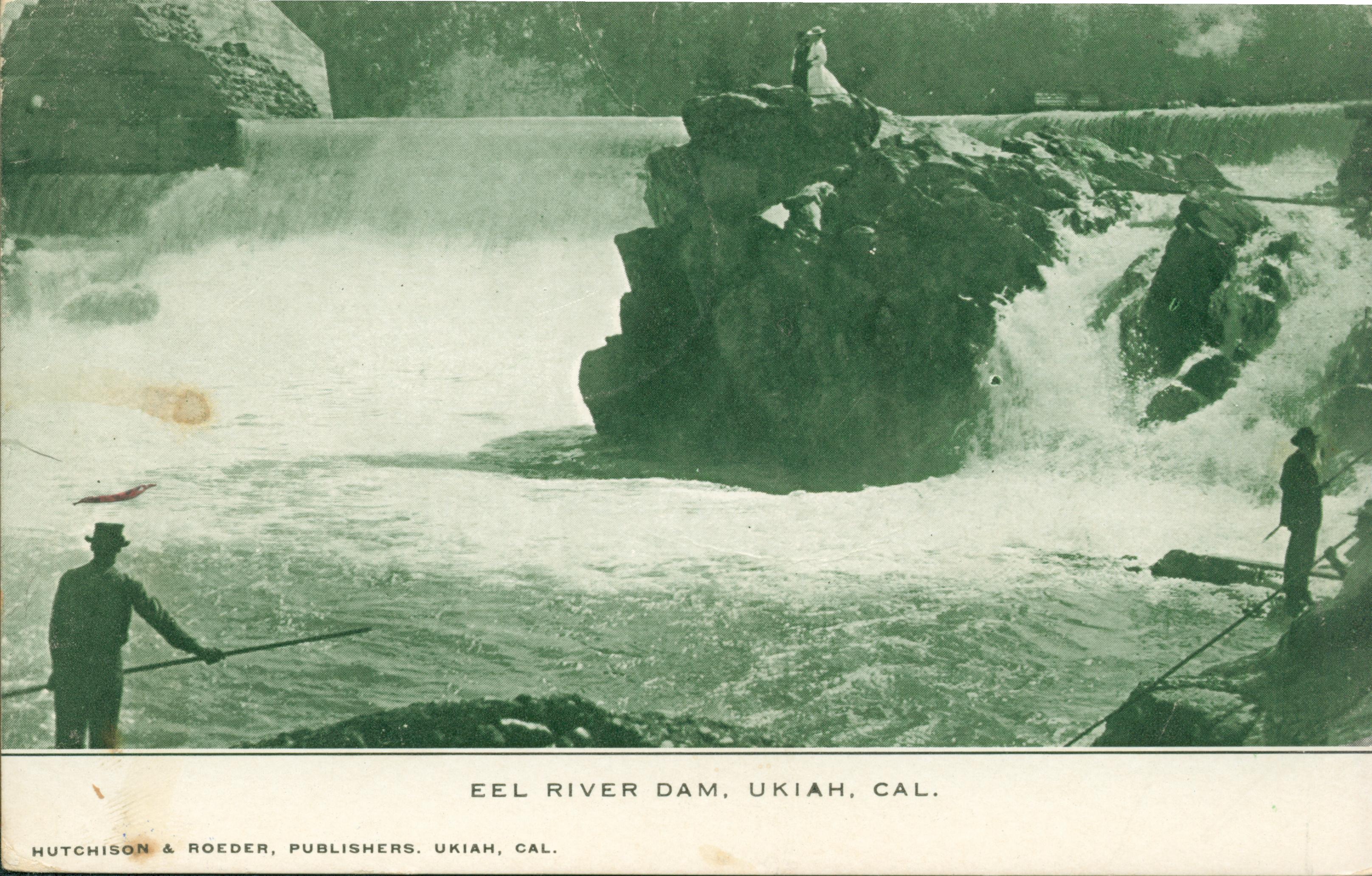 Men spear fishing in the Eel River in Ukiah, waterfalls in background, couple standing on large rock formation in middle of river