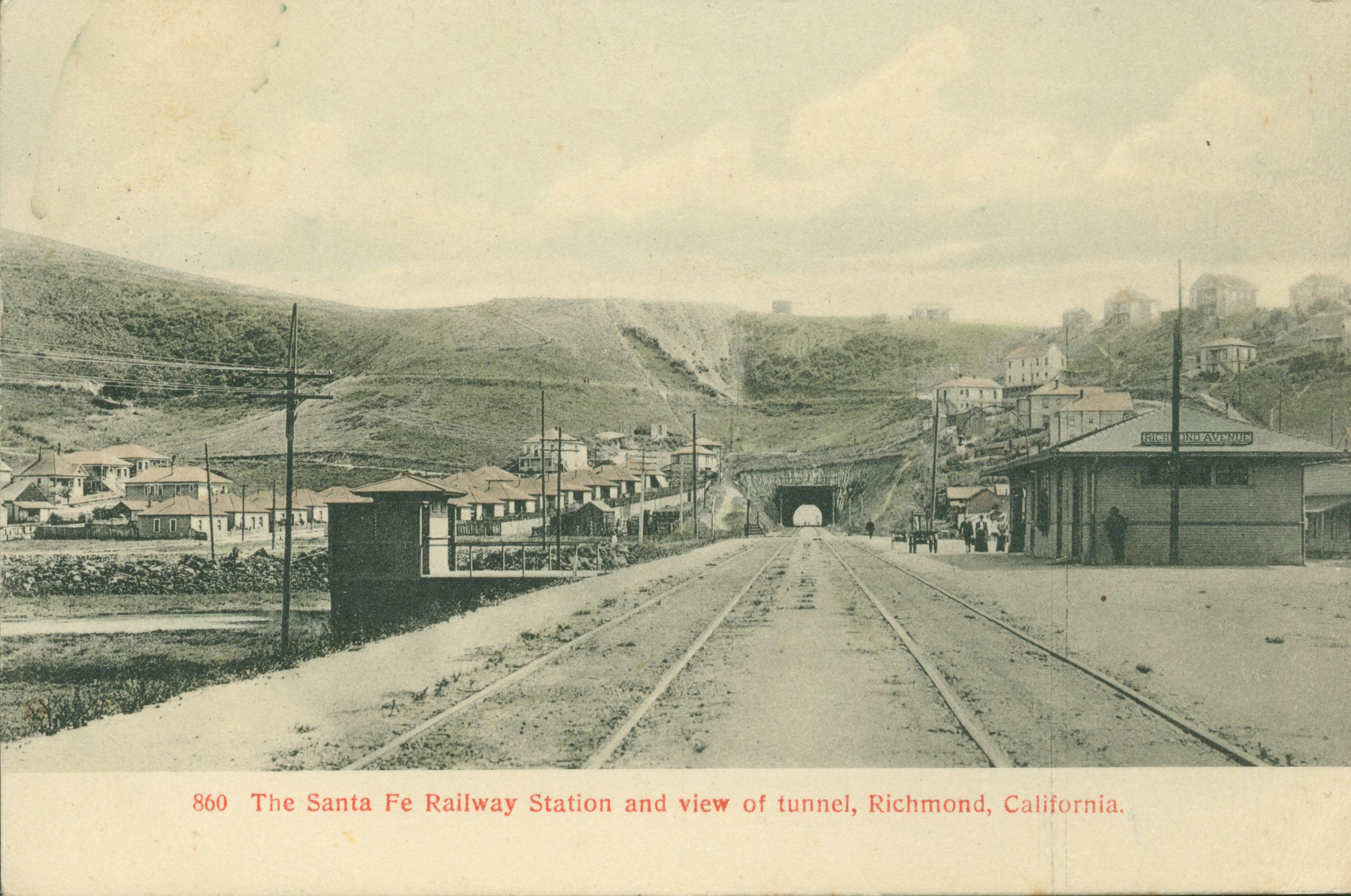 Several buildings with railroad tracks in the foreground leading to a tunnel