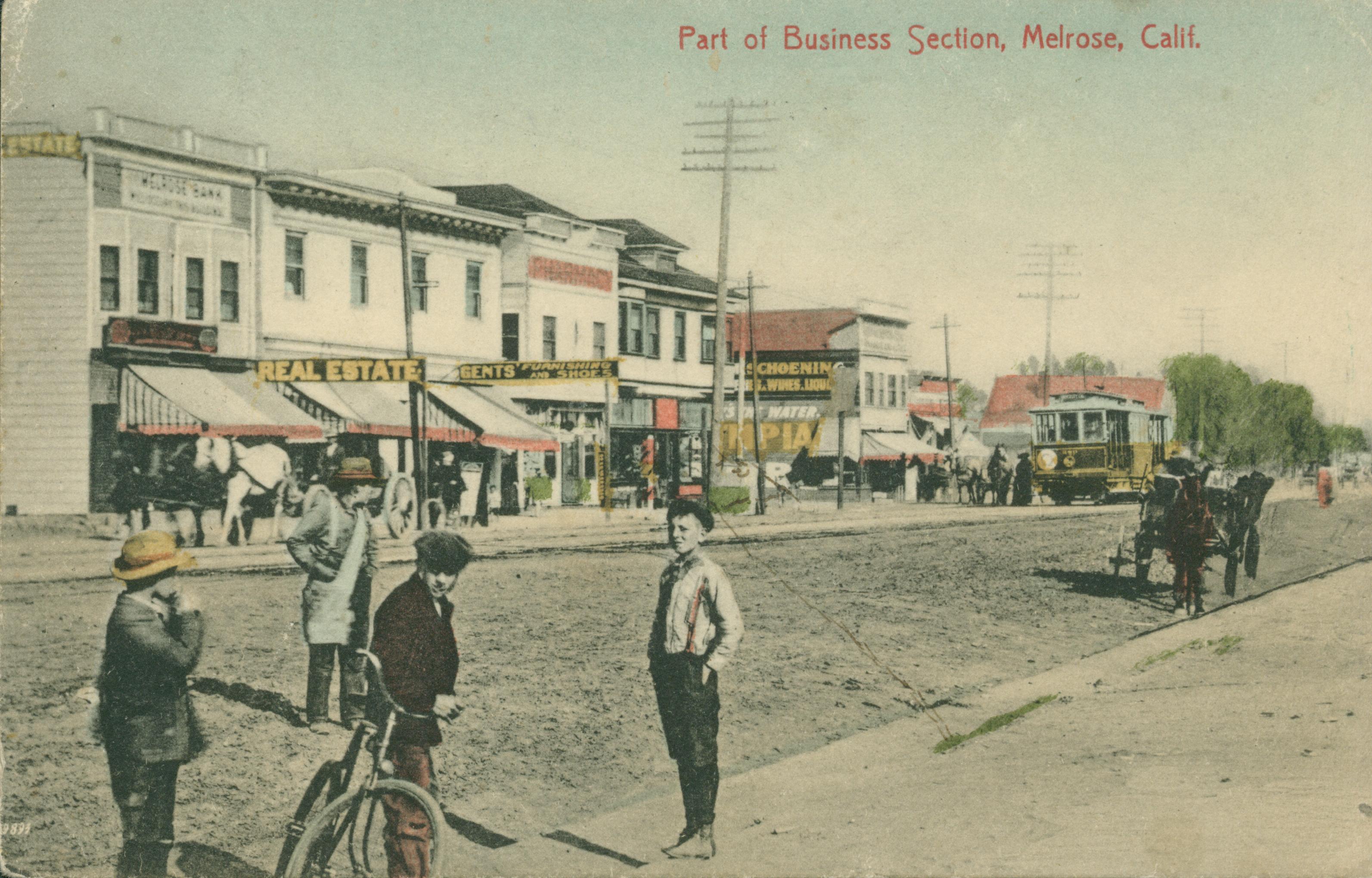 Shows four boys standing on a street in Melrose with businesses in the background