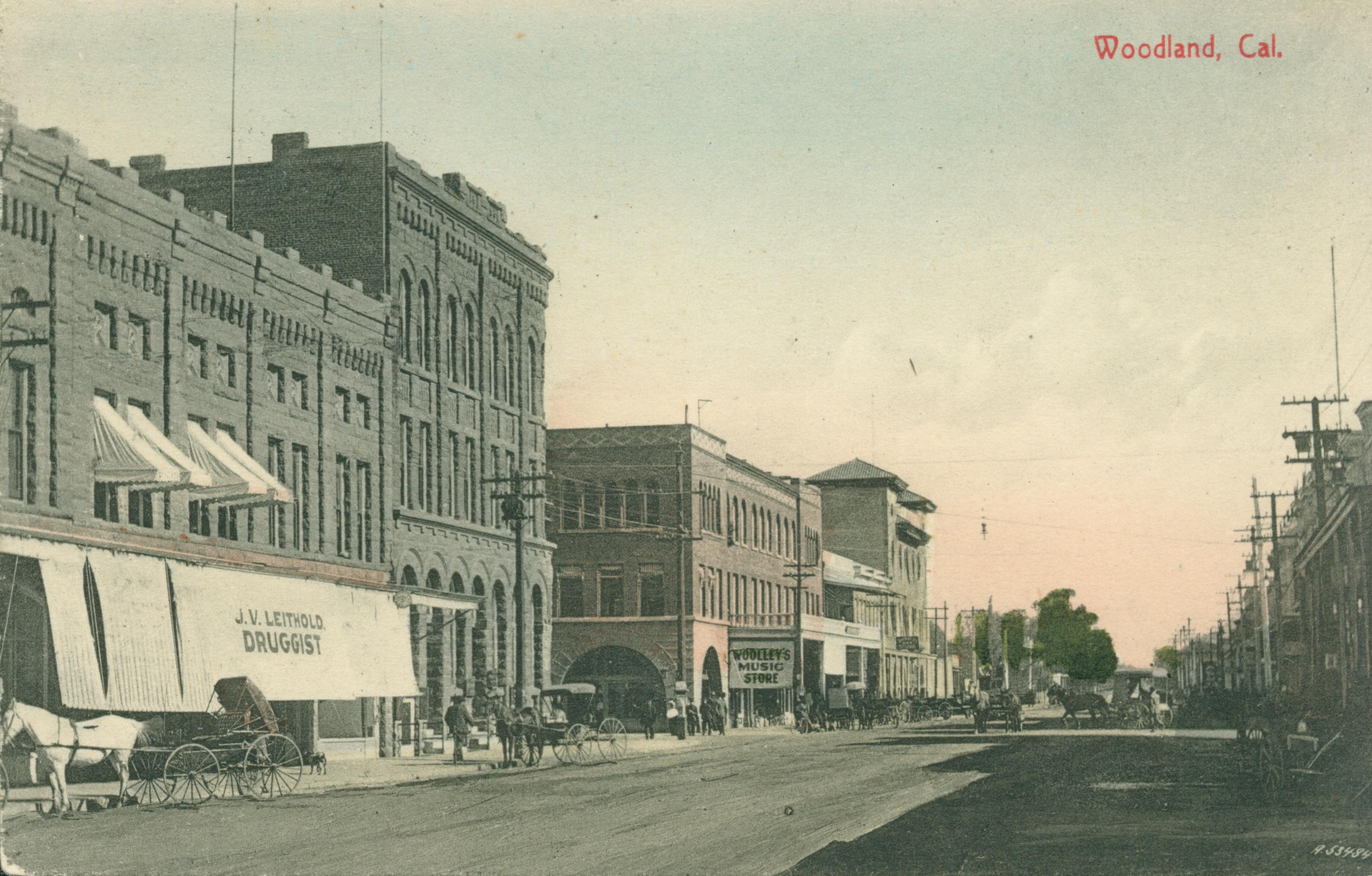 Shows a street in Woodland with the J. V. Leithold drugstore on the left
