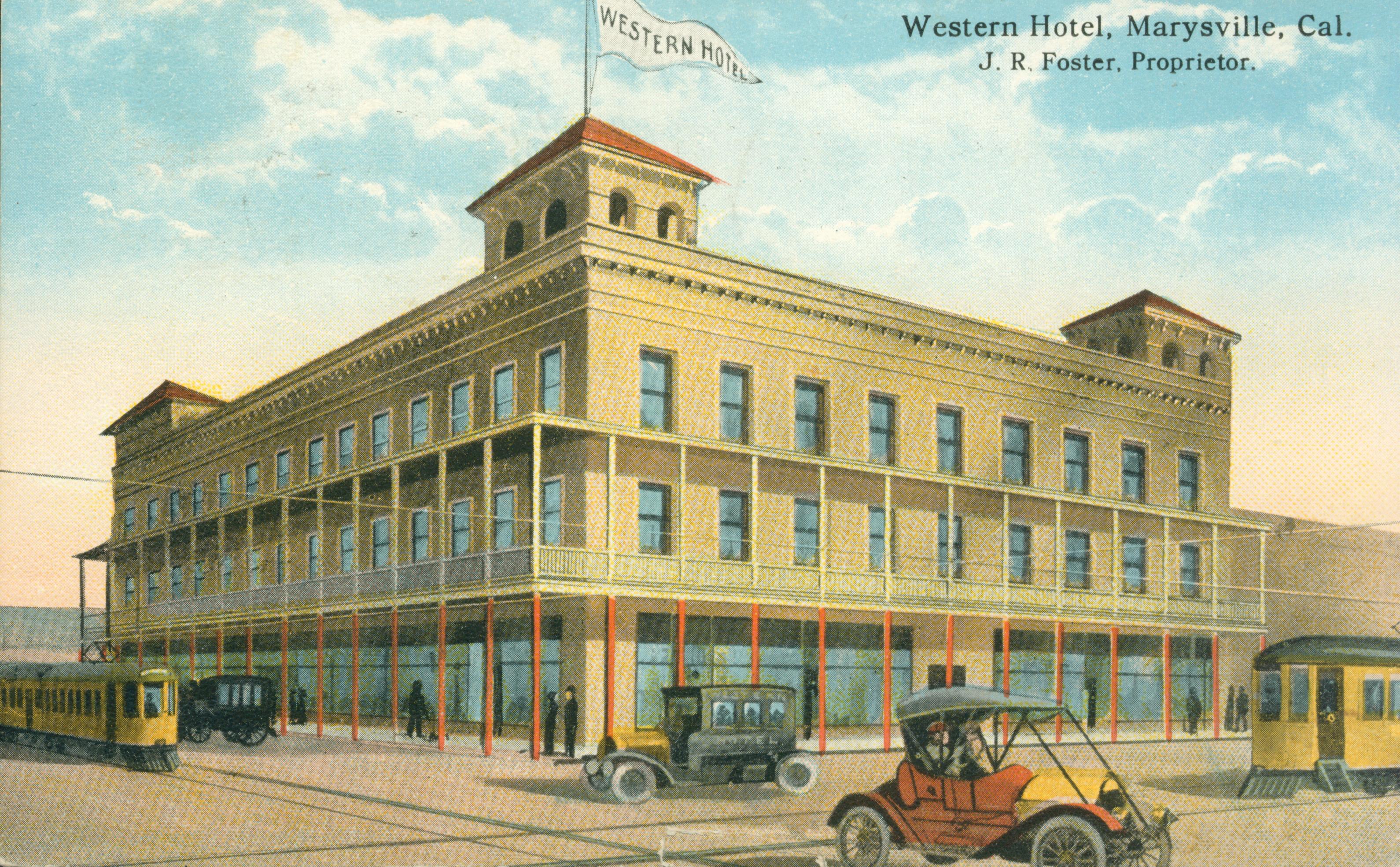 Shows a street-corner view of the Western Hotel with cars and street-cars passing by