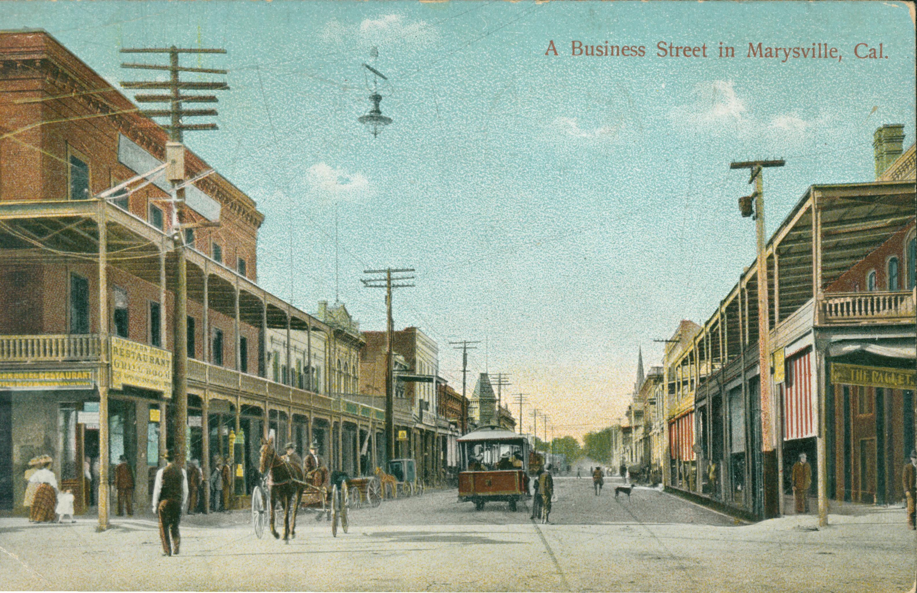 Shows a street in Marysville lined with buildings with a streetcar or trolley in the center of the road and a carriage off to the side.