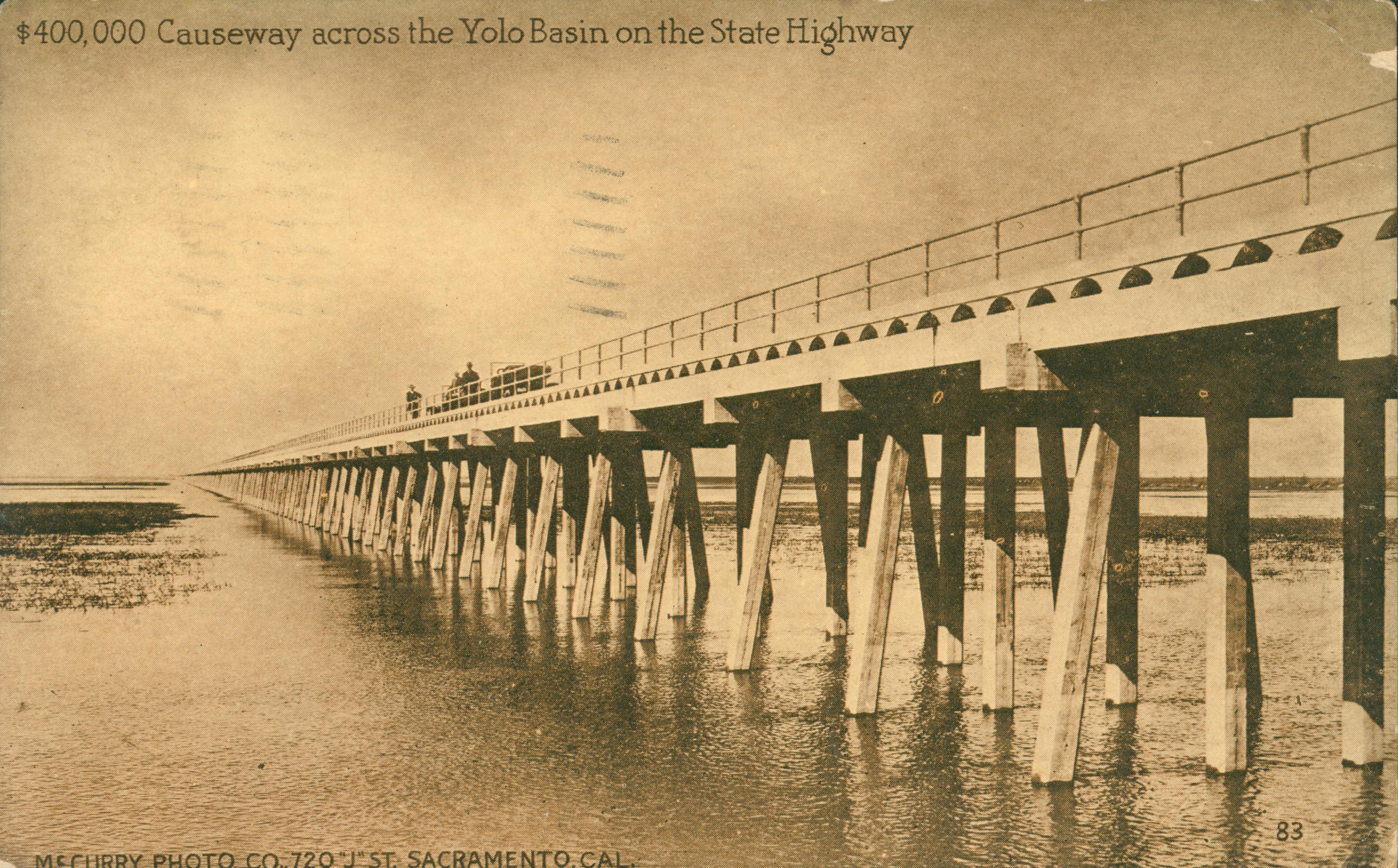 Shows the Yolo Causeway with two cars crossing it