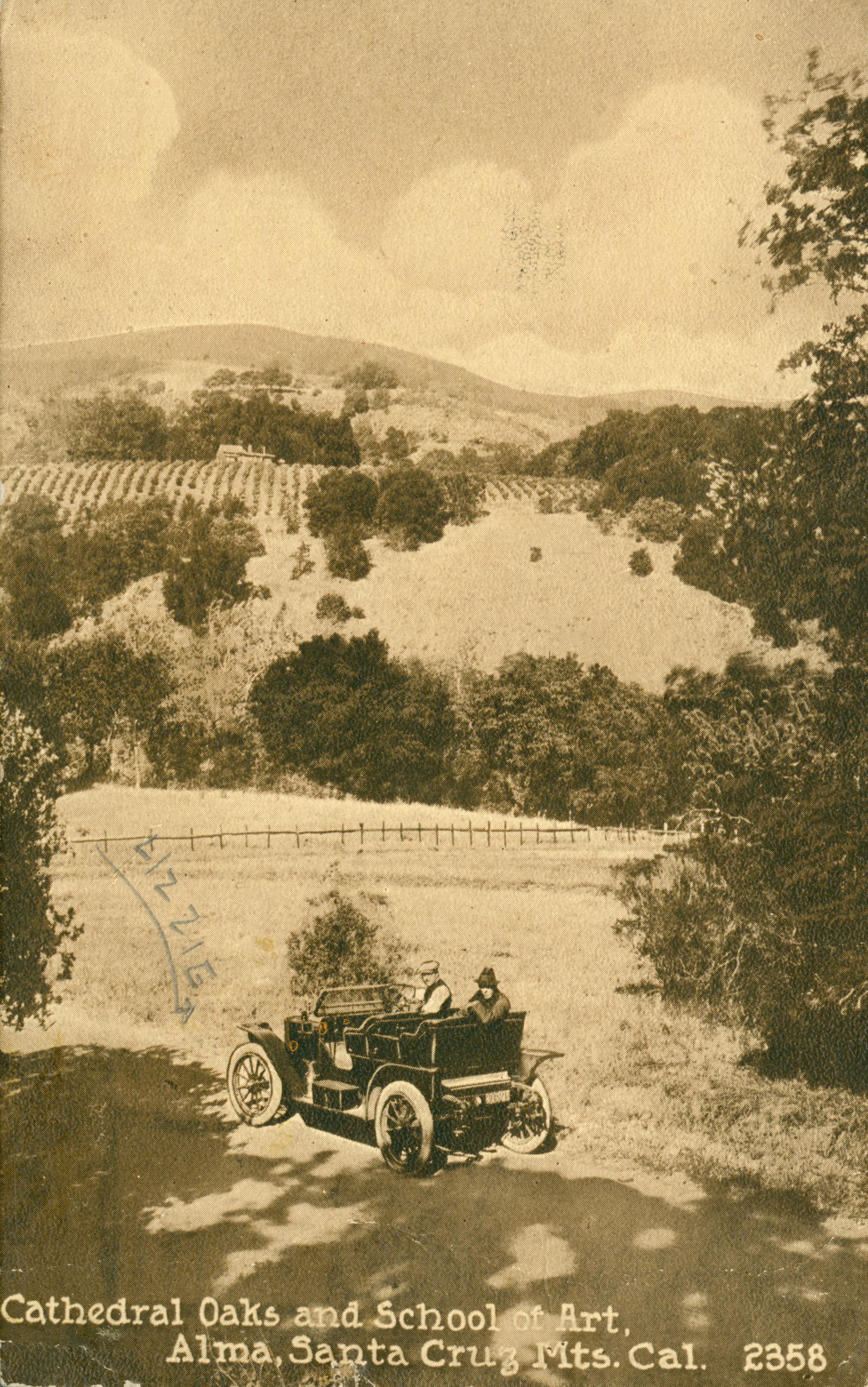 Shows an automobile in a clearing with trees and fields in the background