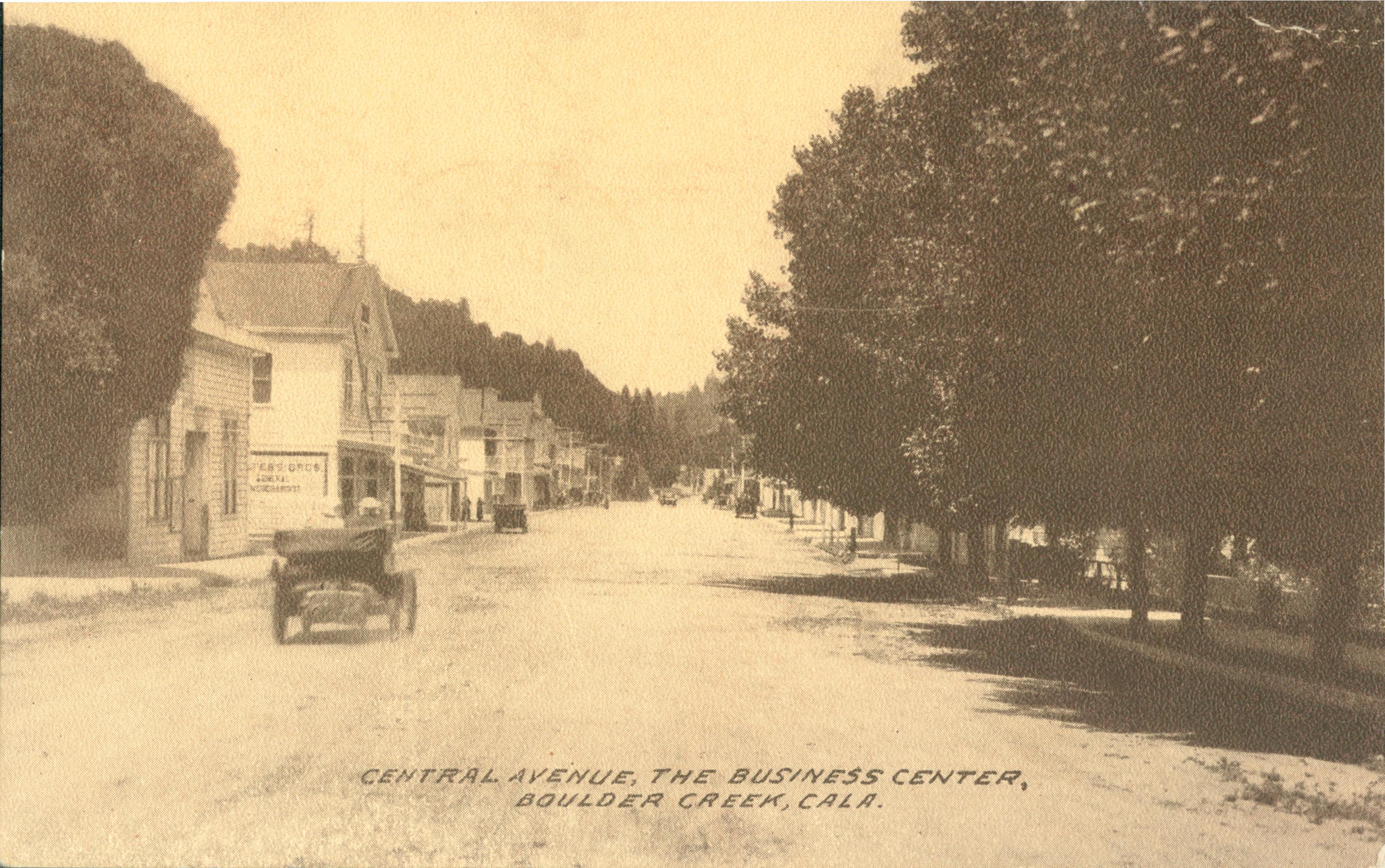 Automobiles traveling down dirt road with buildings to the left and trees to the right
