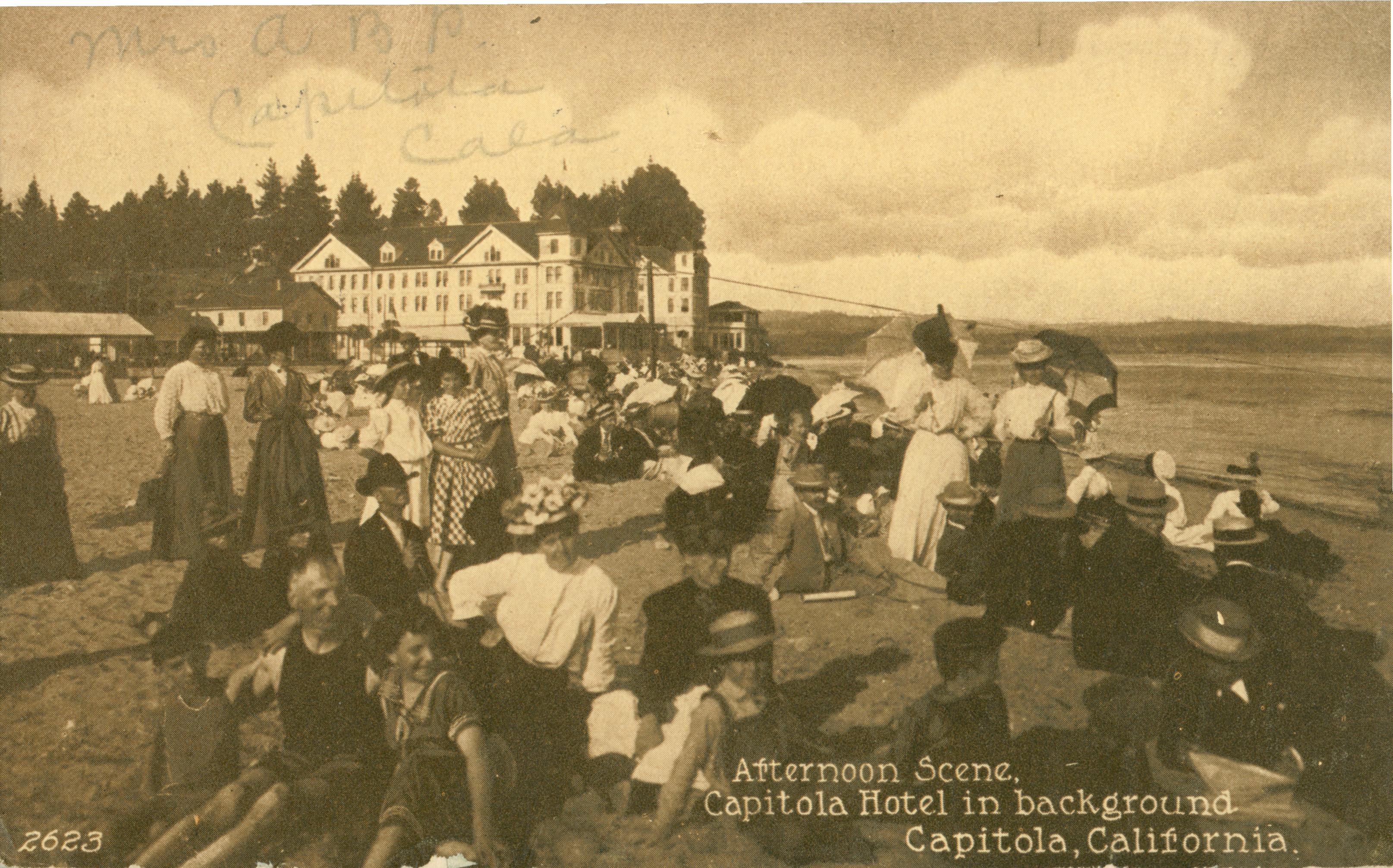 View of people sitting on the beach in front of hotel, exterior view of buildings in background,