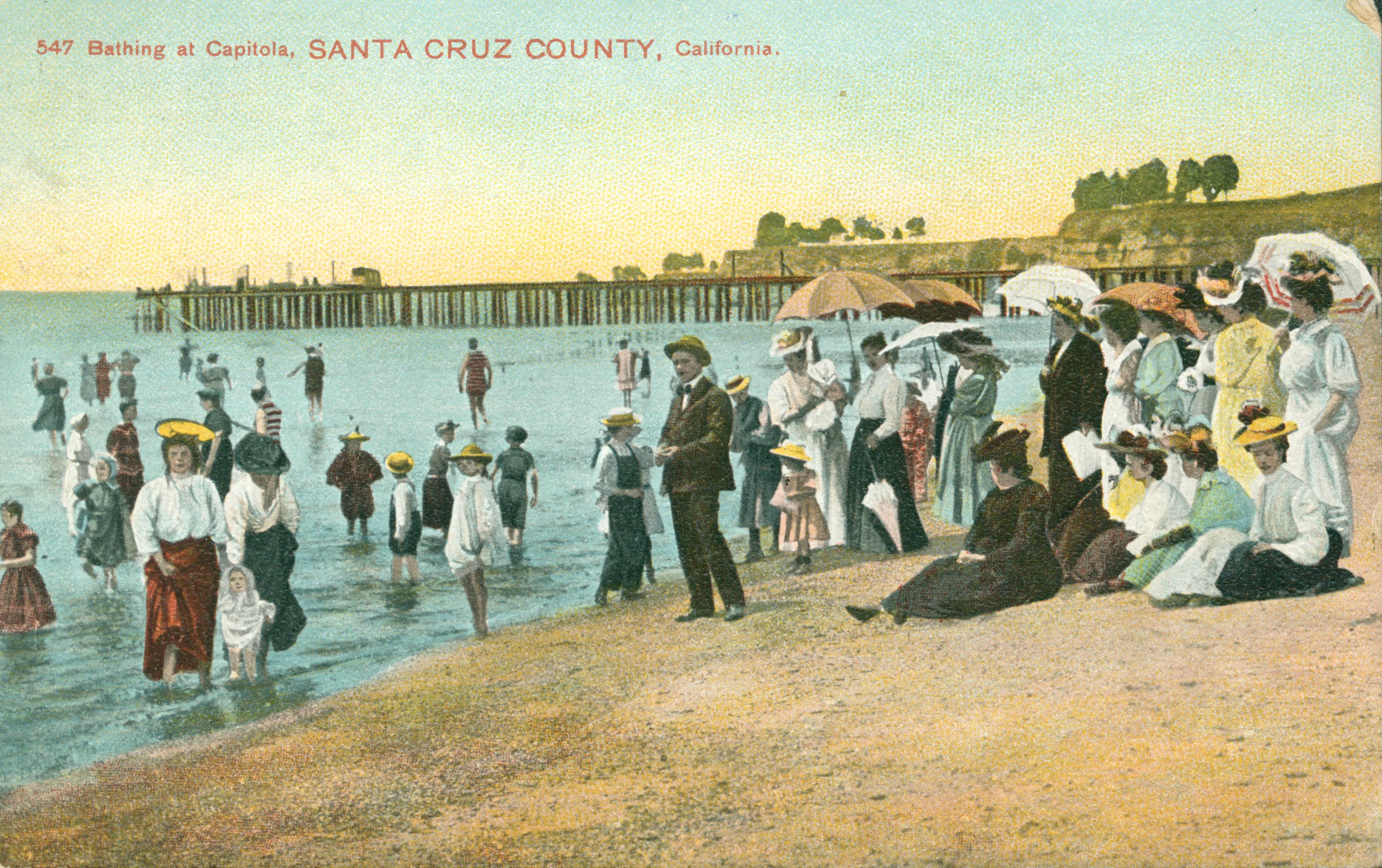 View of people sitting on the beach and swimming in ocean, in front of the casino, exterior view of buildings in background,