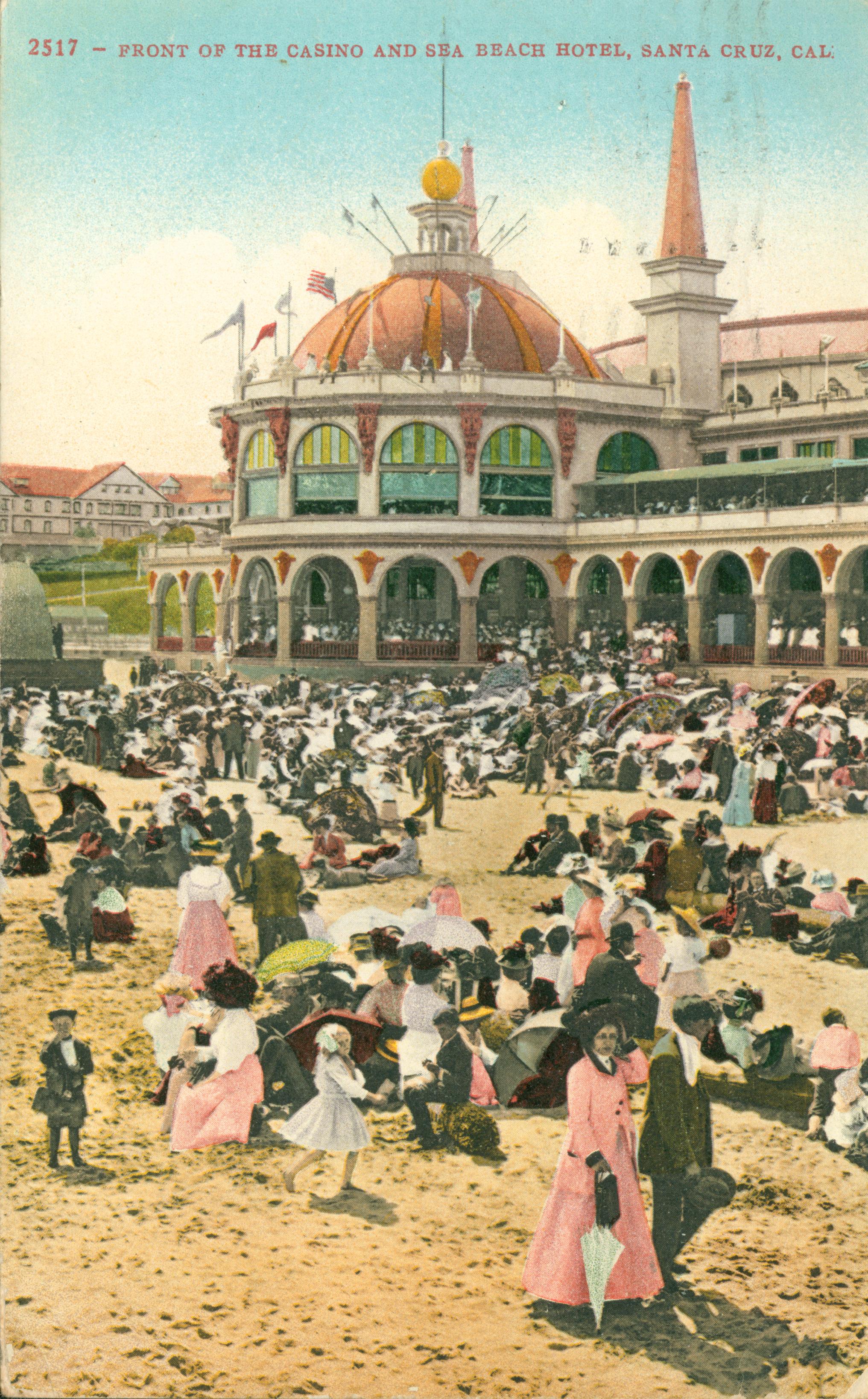 View of people sitting on the beach in front of the casino and Sea Beach Hotel, exterior view of buildings in background